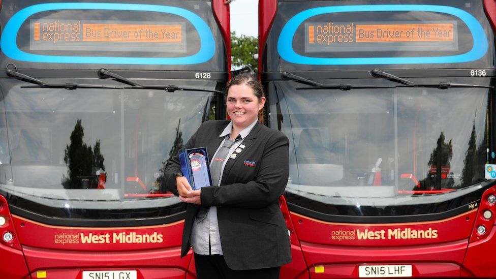 Isobel standing in front of two buses