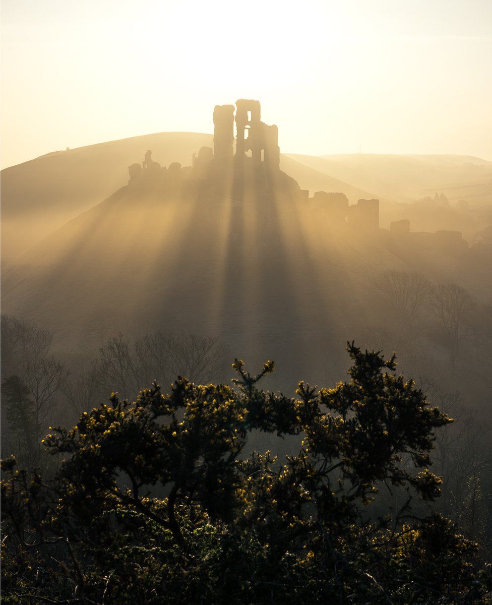 Sunlight streaming through Corfe Castle ruins in England