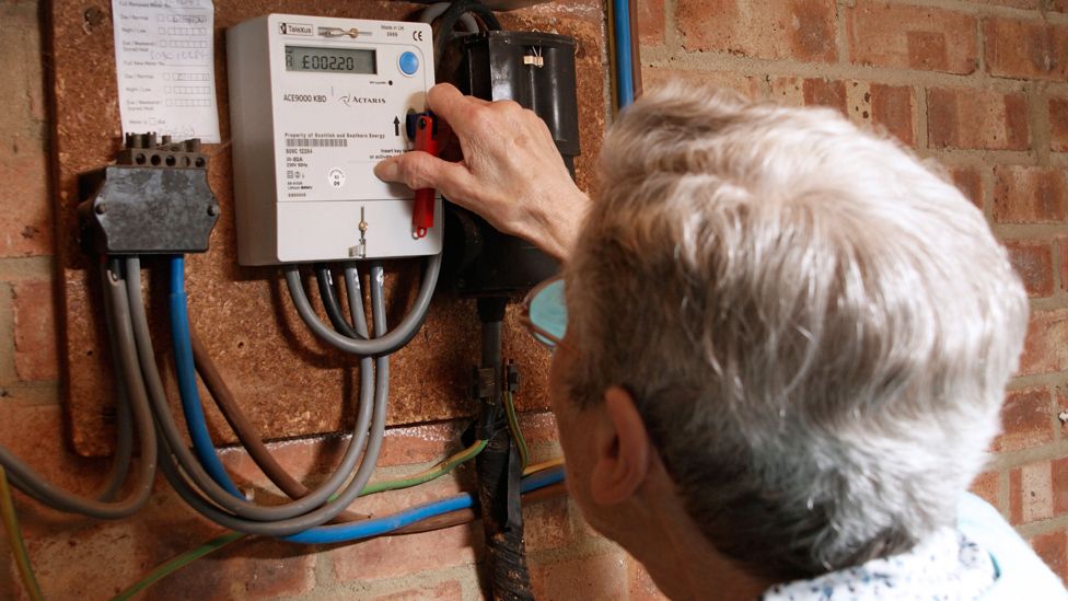 Elderly woman using a prepayment electric meter