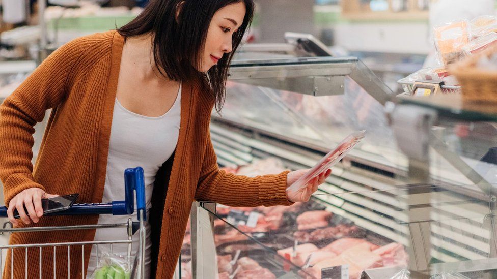 Женщина выбирает мясо в продуктовом магазине