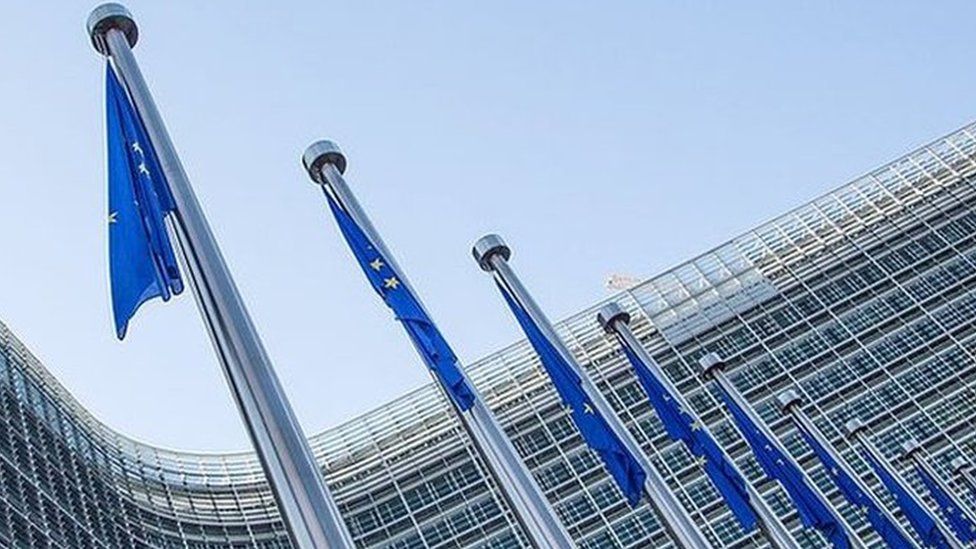 A view of European flags in front of the European Commission headquarters at the Berlaymont Building in Brussels