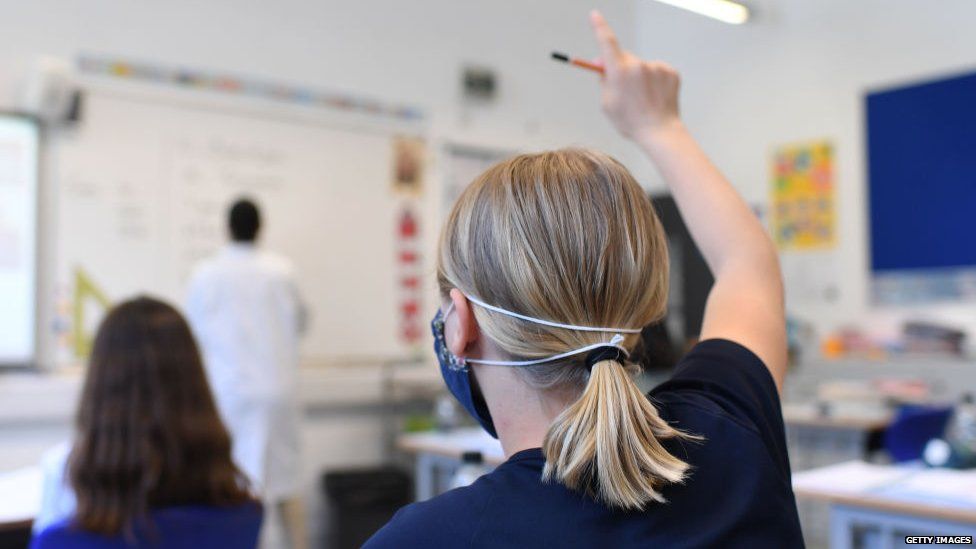 A pupil raises her hand at a school in England