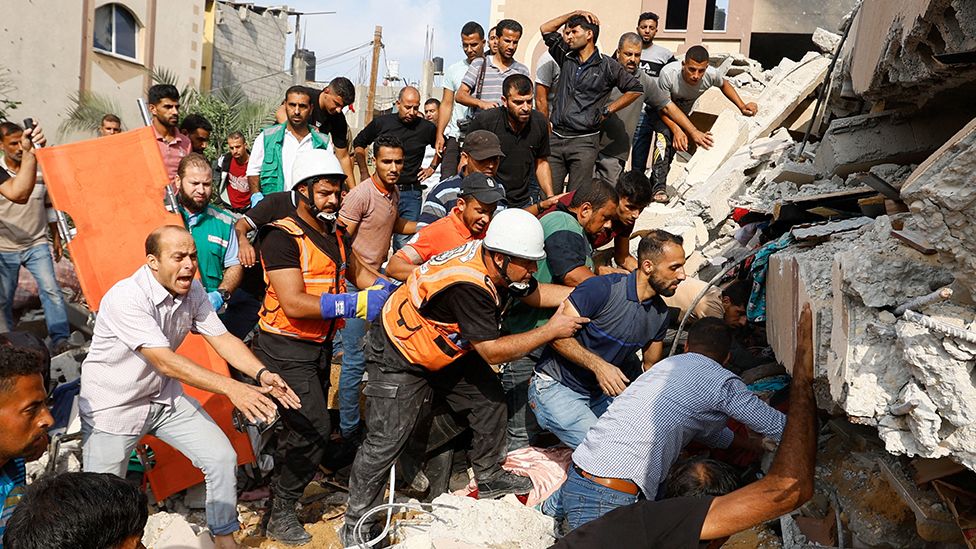 Palestinians search for casualties under the rubble of a house destroyed in Israeli strikes in Khan Younis, in the southern Gaza Strip, October 8, 2023