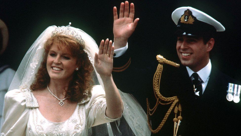 Принц Эндрю и его невеста Сара Фергюсон машут толпе, покидая Вестминстерское аббатство в Лондоне после свадебной церемонии на приеме в Букингемском дворце