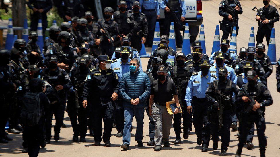 Honduras former President Juan Orlando Hernandez is escorted by members of the National Police as they head towards a helicopter to transport him to the Hernan Acosta Mejia Air Force Base