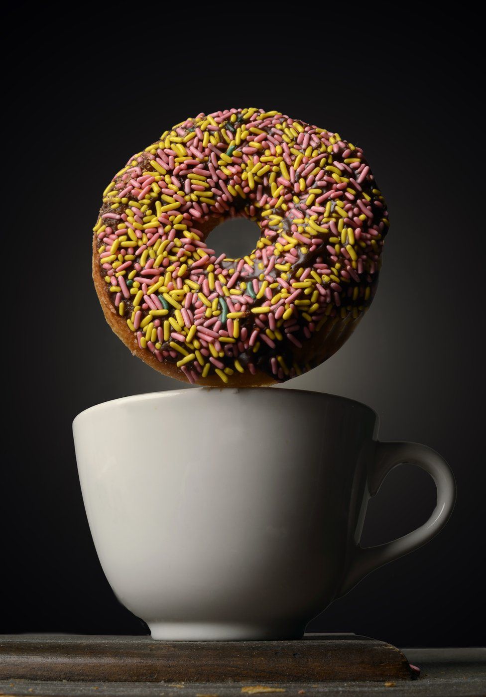 View of a sprinkle doughnut atop a coffee cup,