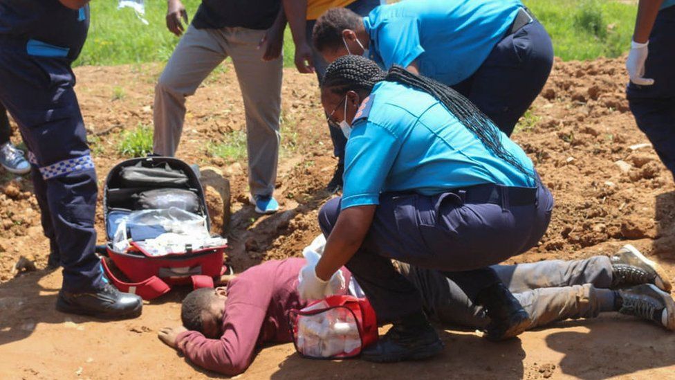 Медработники оказывают помощь человеку, который был ранен полицией во время протестов в Мбабане 20 октября 2021 года.