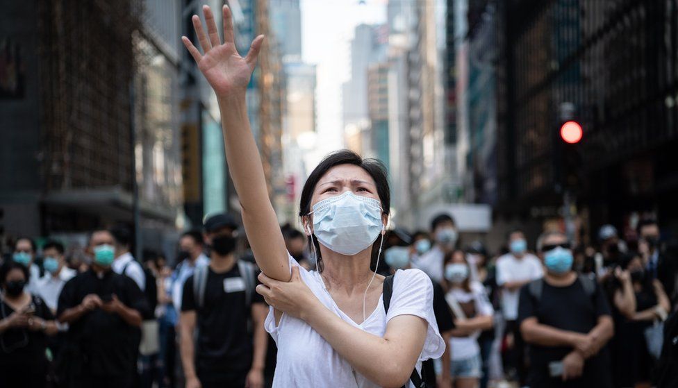 A woman raises her hand while wearing a mask on Friday in Hong Kong