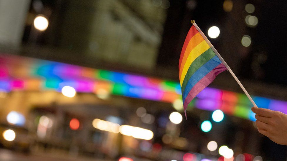 A person waves a Pride flag near The Park Avenue Viaduct lit up in rainbow colors on June 26, 2020 in New York City.