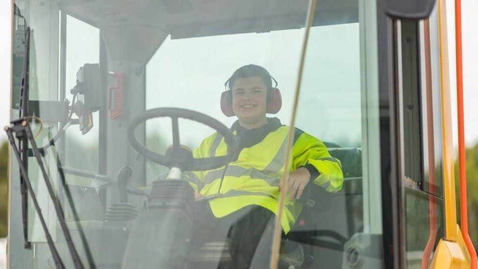 Dominic wearing a high vis jacket in a heavy-duty machine in Norfolk