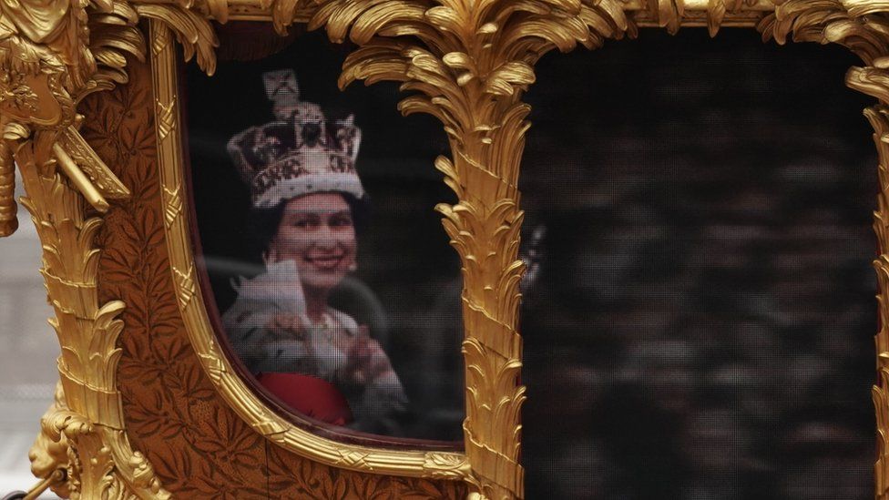 A close up of footage of the Queen at her coronation on the golden coach