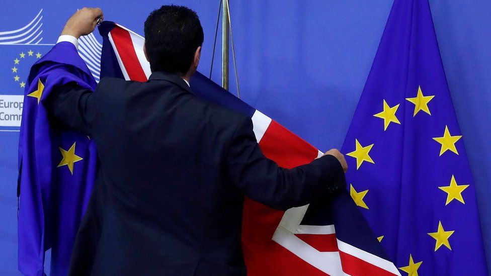 EU official hanging a Union Jack flag next to an EU flag