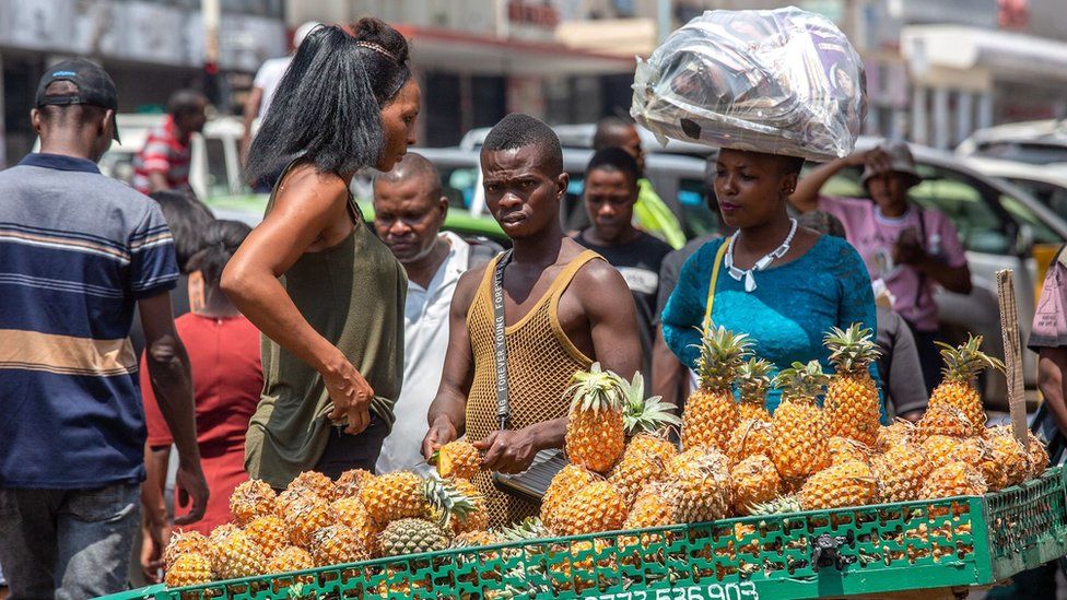 People selling pineapples in the street with passersby