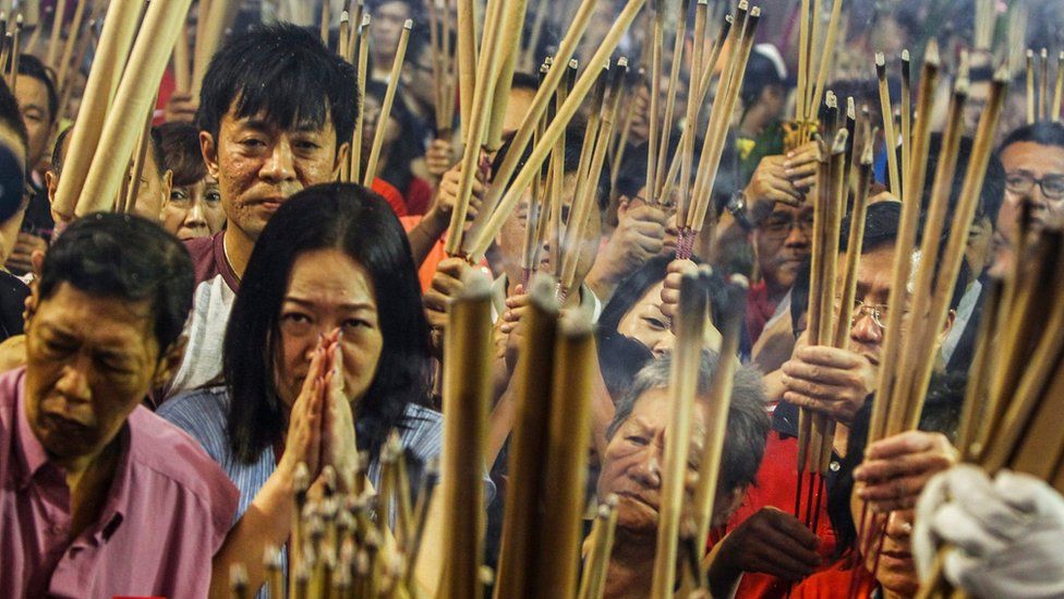 A female devotee (L) offers up prayers for the new year after placing joss sticks into an urn at the Kwang Im Tho temple in Singapore, 07 February 2016.