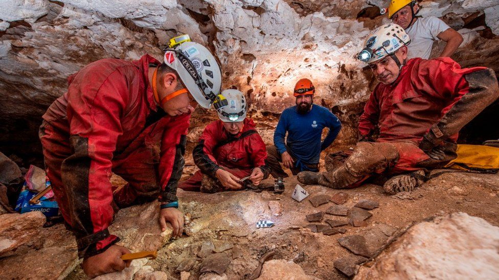 Archaeologists of the National Institute of Anthropology and History (INAH) observe fragments of pottery in a cave