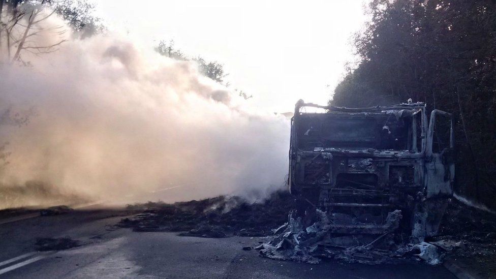 The burnt remains of the lorry with smoke still visable