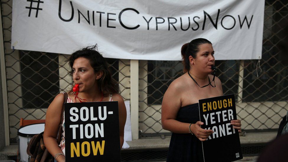 Women with signs saying "unite Cyprus now and "Solution Now"