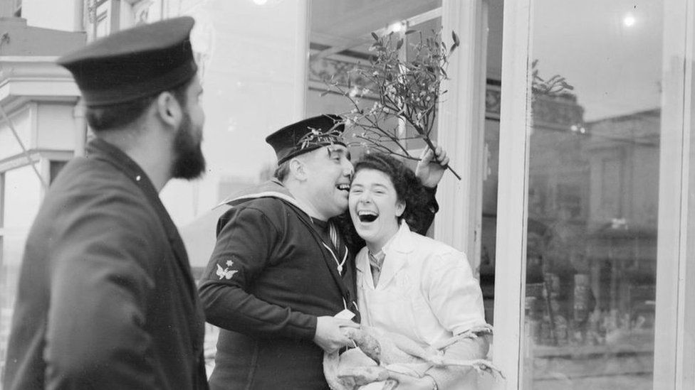 Submariner bothers a lady butcher with mistletoe