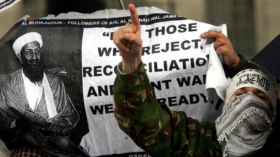 A demonstrator protests next to a banner of the contoversial Islamic group Al-Muhajiroun, depicting Osama Bin Laden, outside Downing Street, London, May 4, 2004.