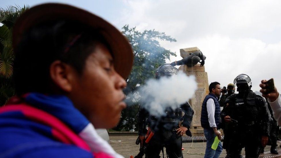 An indigenous person performs a ritual in front of the authorities after protesters knocked down the statue of the founder of the city, Spanish conqueror Sebastian de Belalcazar, during the protests against the tax reform called by the workers" centrals in Cali, Colombia, 28 April 2021.