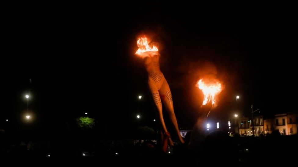 Человек несет горящий манекен во время акции протеста в Мехико