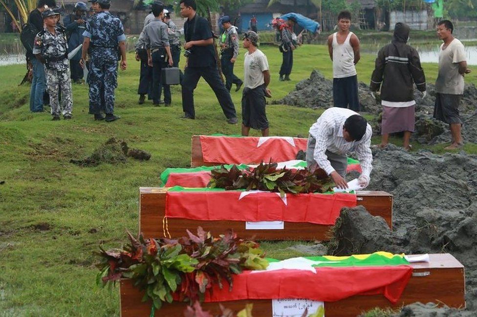 Myanmar border police prepare flag draped coffins bearing nine bodies of border guards killed in mysterious raids during a funeral ceremony at a cemetery in Maungdaw in Rakhine State on October 11, 2016.