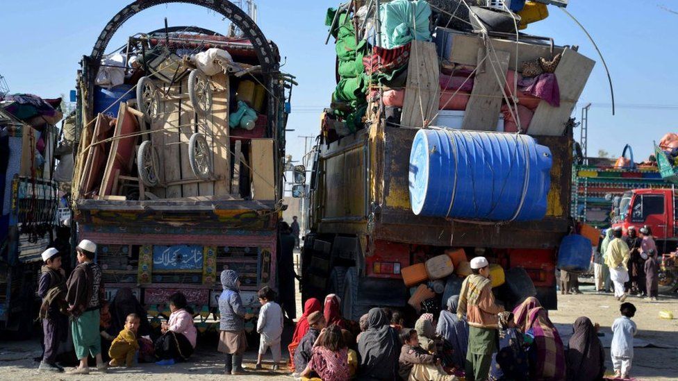 Afghan refugees sit by their belongings