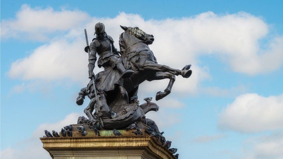 Close up of bronze sculpture showing St George on horseback slaying a dragon