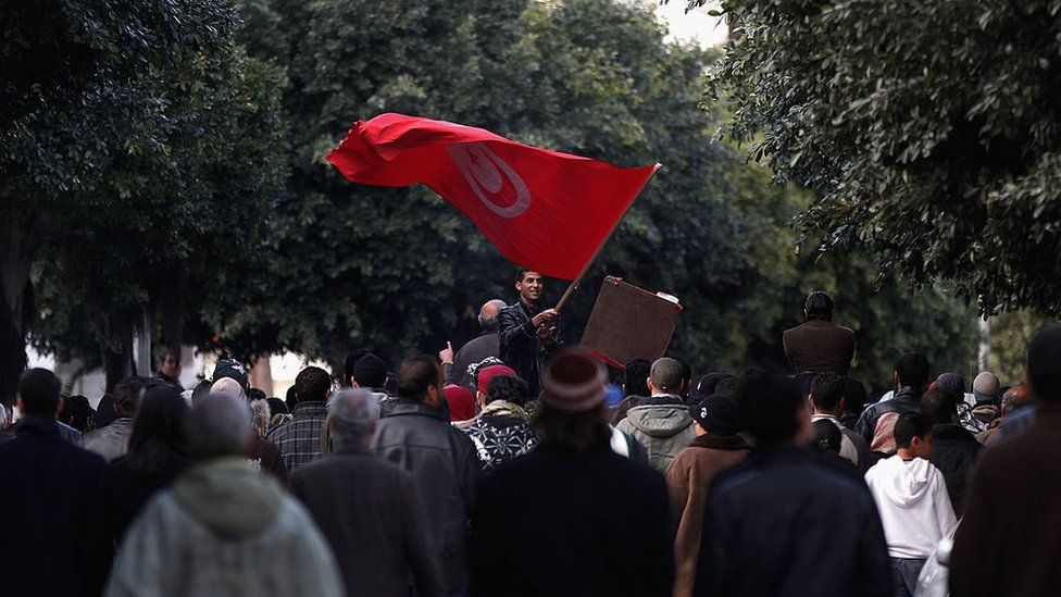 Tunisian man waves flad at demonstration