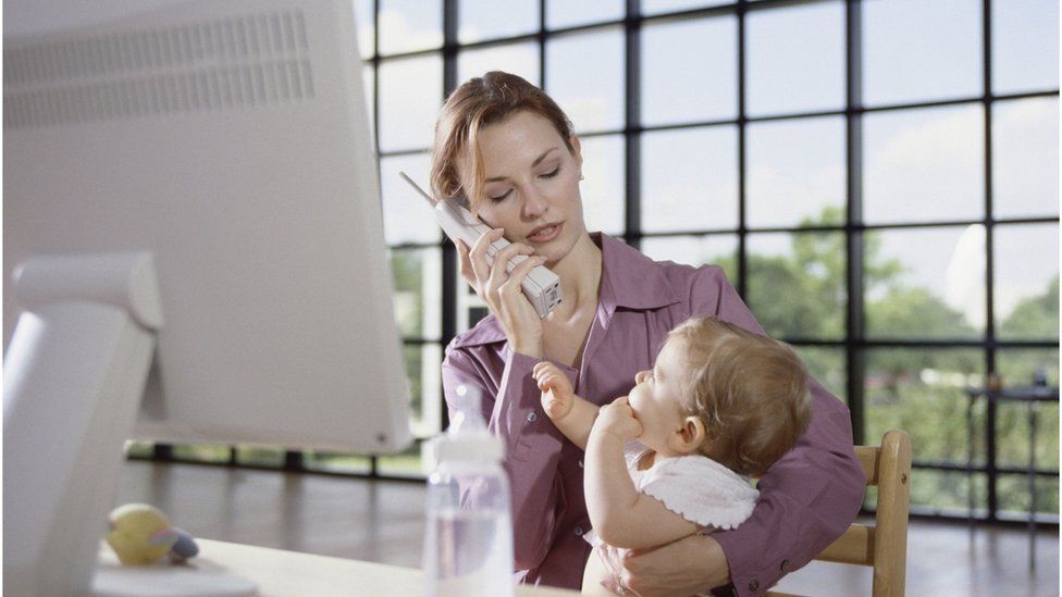 Woman holding a baby at her office desk