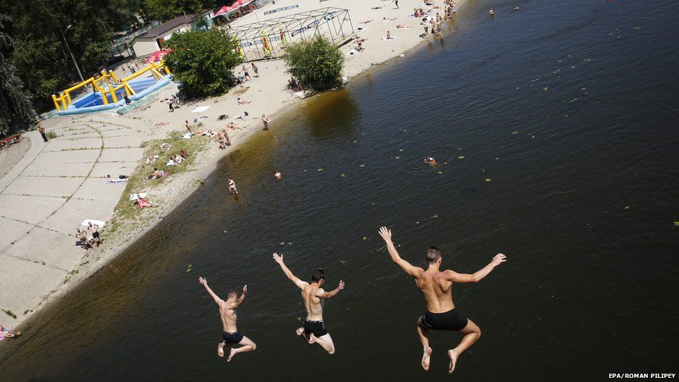 Three boys jump from a bridge into a river