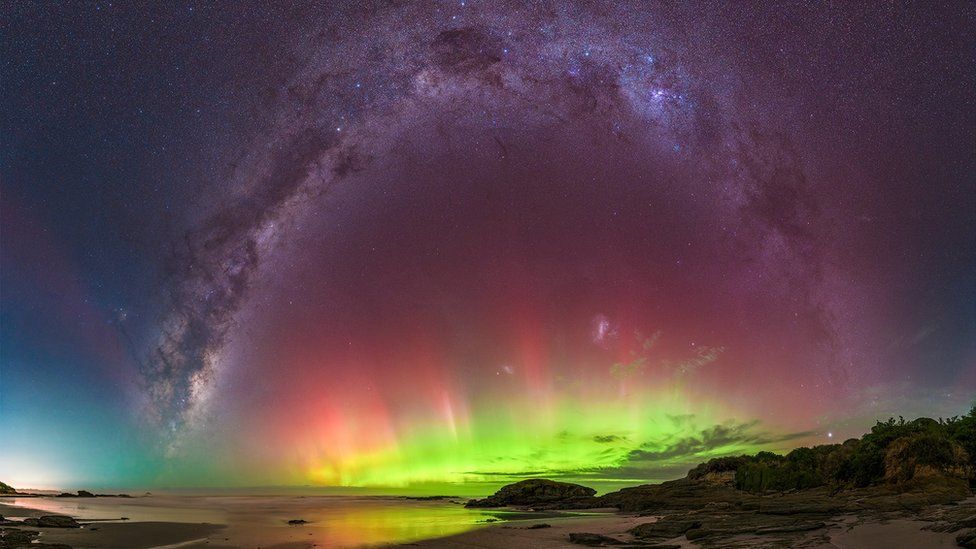 Μια επίδειξη Aurora Australis με πράσινα, μοβ και ροζ φώτα φαίνεται πάνω από την παραλία Brighton στο Dunedin της Νέας Ζηλανδίας.