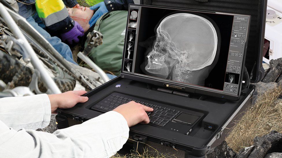 An emergency worker looking at an X-ray image beside a road in a mock up, practise situation