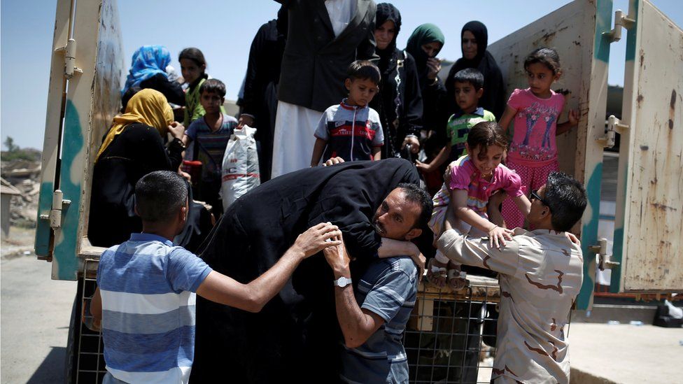 A man assists an elderly woman as civilians flee the fighting in the Iraqi city of Mosul (19 June 2017)