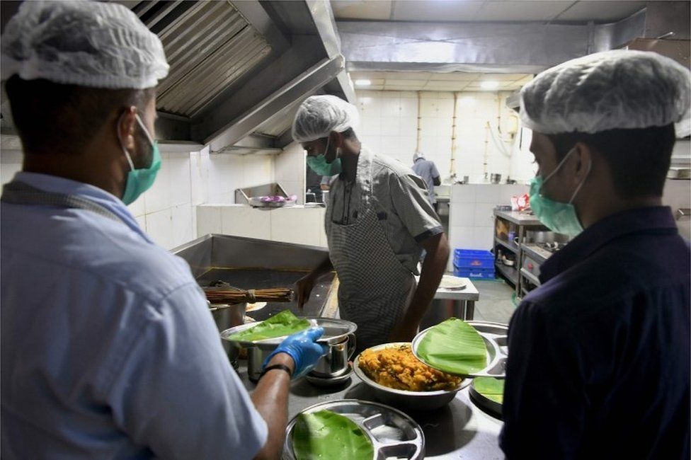 Staff members of the Indian Railway Catering and Tourism Corporation (IRCTC) wear facemasks, as a preventive measure againsts the spread of the COVID-19 coronavirus outbreak, as they prepare food for customers in a restaurant at Bangalore City Railway Station, on March 4, 2020
