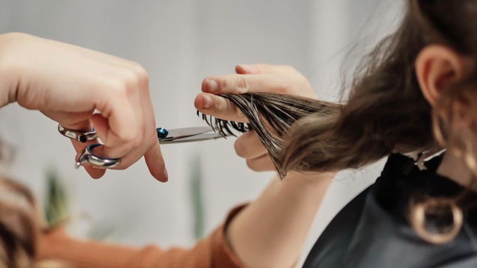 Hairdresser holding scissors cutting hair