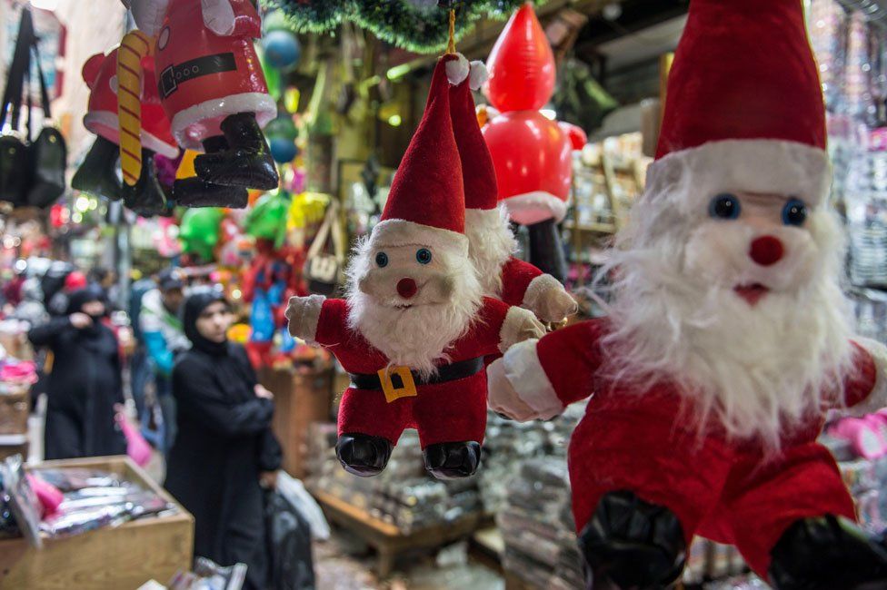 People walk near Santa Claus toys displayed for sale for Christmas and new year in Cairo, Egypt, 25 December 2018