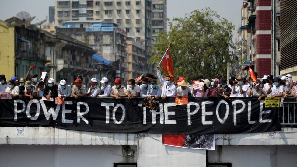 Demonstran berdiri di belakang spanduk saat mereka memprotes kudeta militer di Yangon