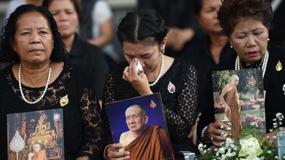 Women hold pictures of Thailand"s most senior Buddhist monk, the late Supreme Patriarch Somdet Phra Nyanasamvara