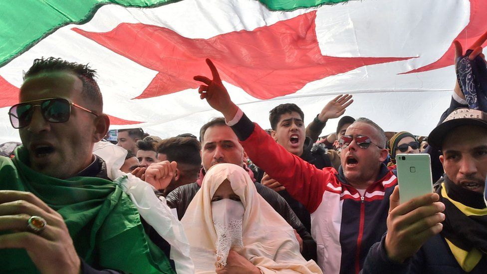 Algerians chant slogans under a national flag during a protest rally against ailing President Bouteflika's bid for a fifth term in power, in the capital Algiers on 1 March 2019