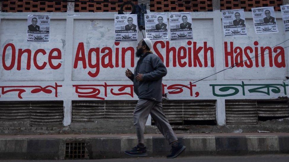 A man jogs by election posters of Awami League