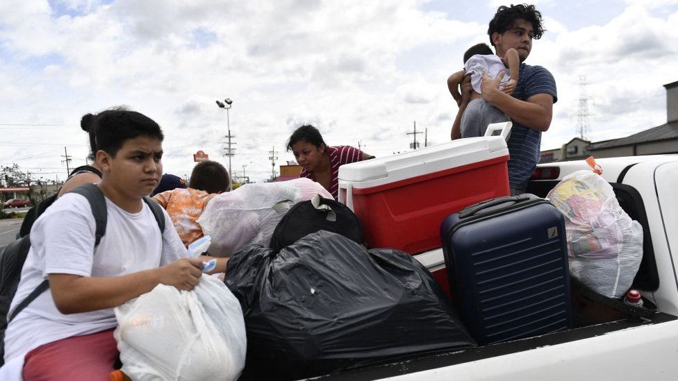 Members of the Villalobos and Martinez families gather their belongings after being rescued in Laplace, Louisiana, on August 30, 2021 after Hurricane Ida made landfall.