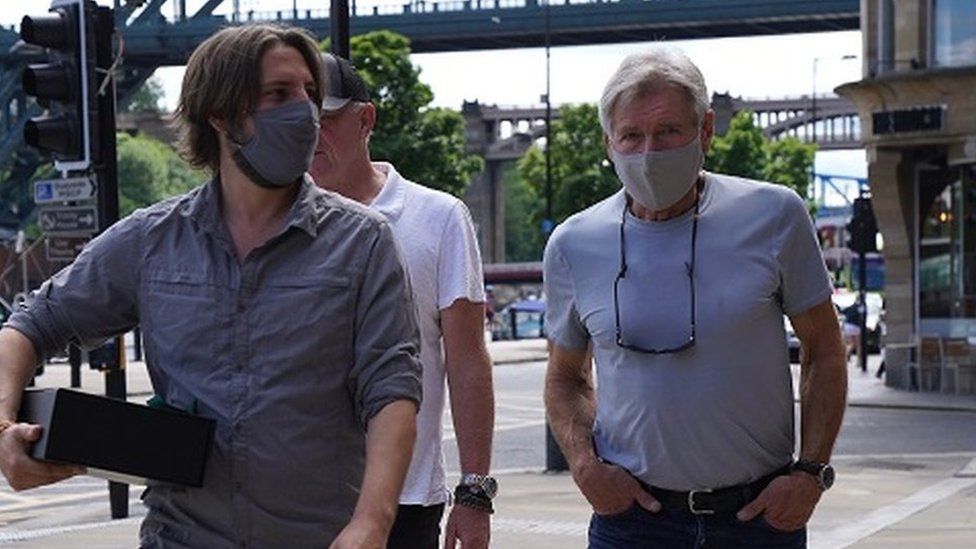 Harrison Ford, wearing a face mask, on Newcastle Quayside with the Tyne Bridge in the background