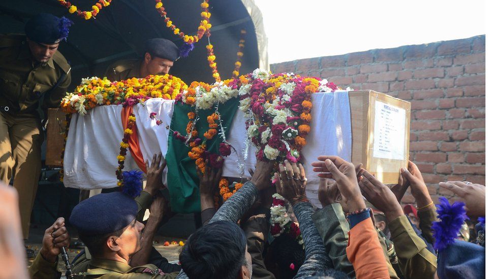 Mourners touch the coffin as they take part in the funeral procession for Indian Central Reserve Police Force trooper Mahesh Kumar Meena at Meja village, near Allahabad