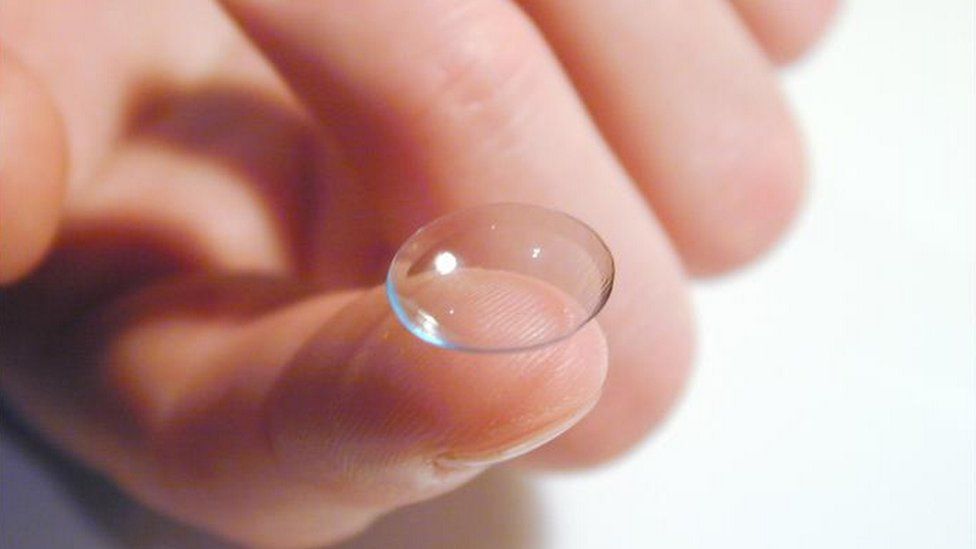 A contact lens balancing on a finger