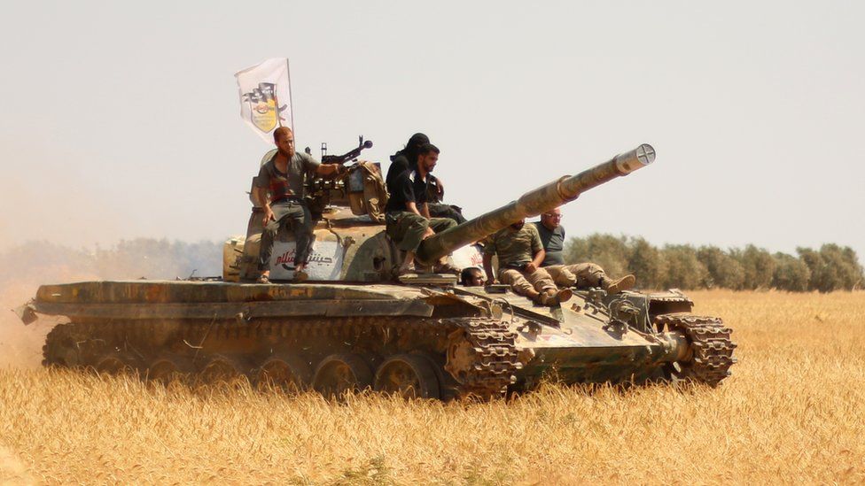 Rebel forces from Jaysh al-Islam (Army of Islam) stand on a tank as they hold a position on August 24, 2015 near the frontline in the al-Zahra area, on the northwestern outskirts of Aleppo