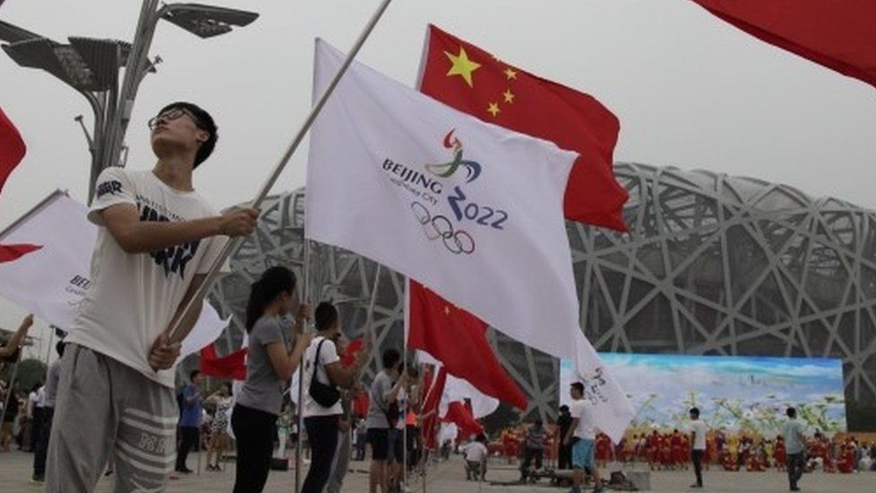 Chinese performers hold up flags of China and Beijing 2022 during a rehearsal in Beijing. Photo: 30 July 2015