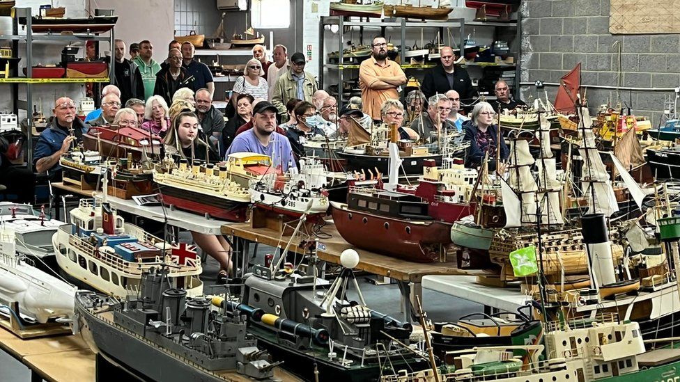 Model boats in front of bidders at an auction
