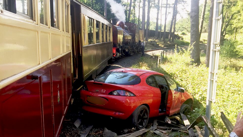 A car damaged by a collision with a steam train.