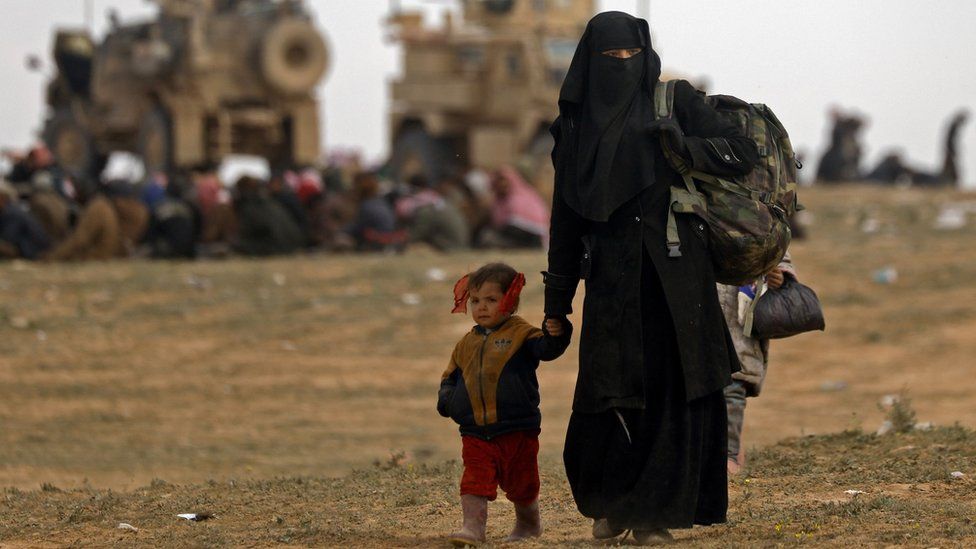 A woman and child flee the last IS-held pocket of territory near Baghouz, Syria, on 13 February 2019